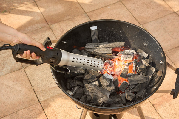 BBQ aansteker blaast houtskool in een kogelbarbecue gloeiend